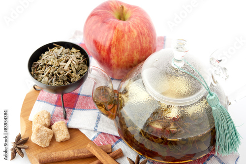 Ripe apple, cinnamon and fruit drink in glass teapot on white