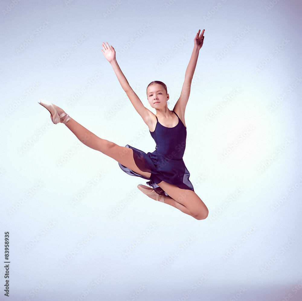 Fototapeta premium Beautiful young ballet dancer jumping on a gray background. 