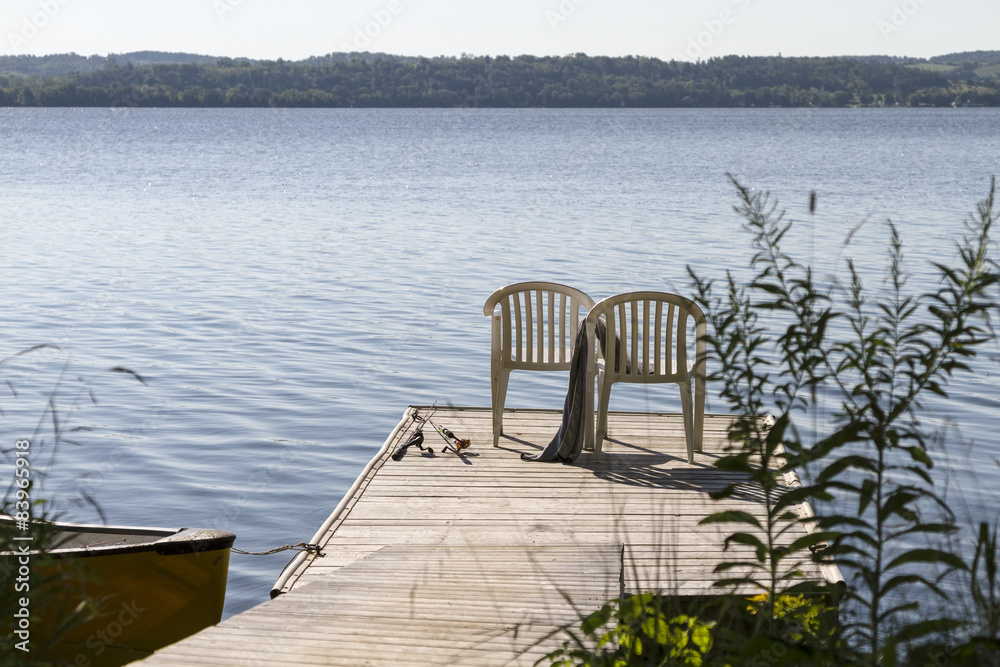 2 Stühle auf einem Holzdeck am See mit Angeln