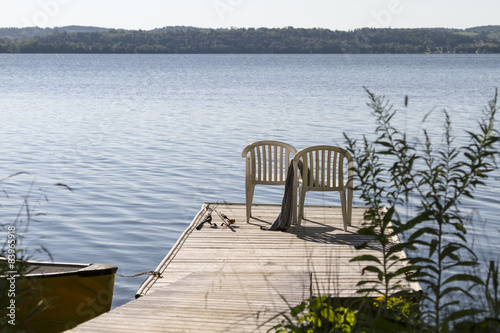 2 Stühle auf einem Holzdeck am See mit Angeln
