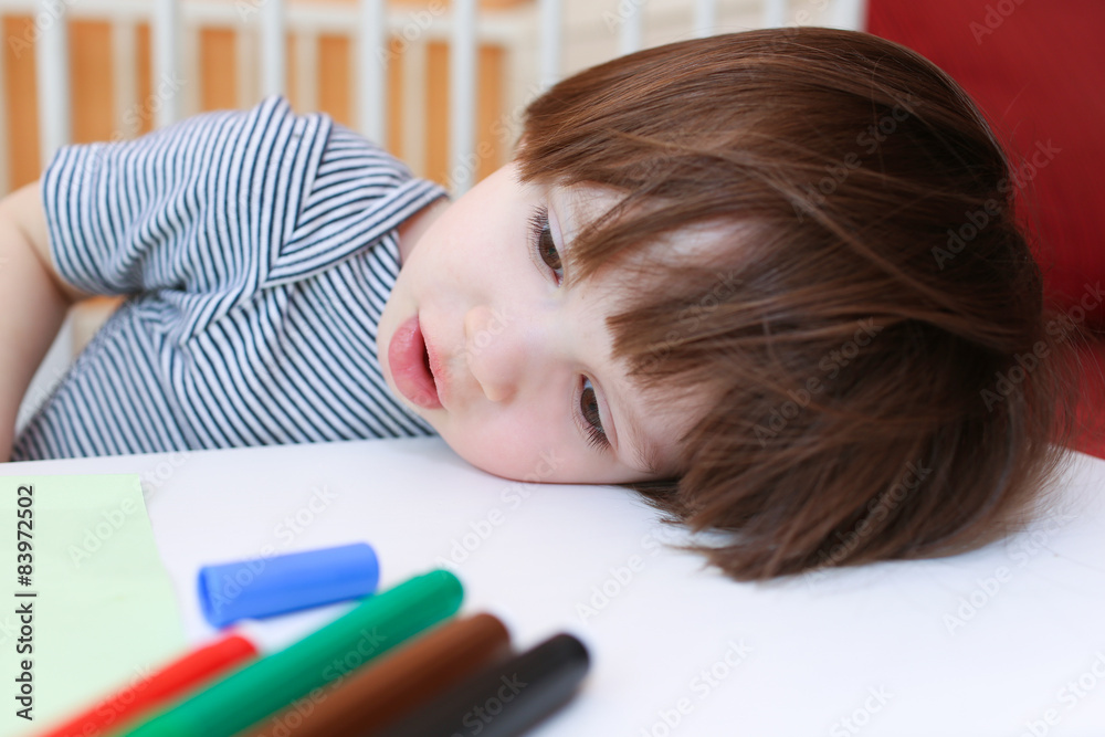 Tired little boy with felt pens rest his head on a table Tired little boy with felt pens rest his head on a table