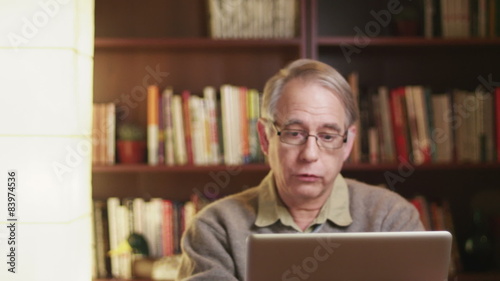 A older man talking over a video chat using his laptop.