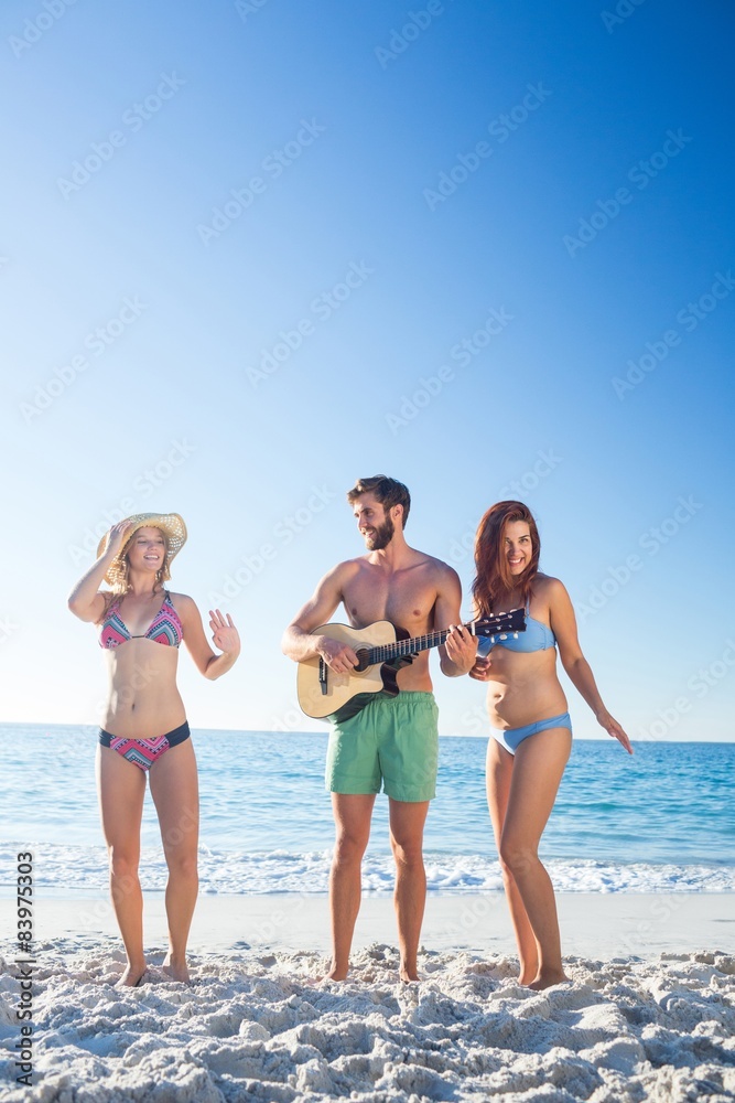 Handsome man playing guitar and his friends dancing Handsome man playing guitar and his friends dancing