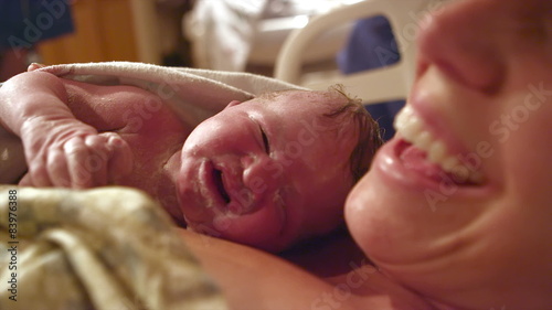 A newborn baby born just minutes before on her mothers chest photo