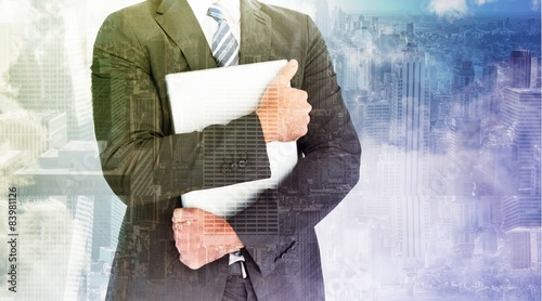 Composite image of businessman holding his laptop tightly