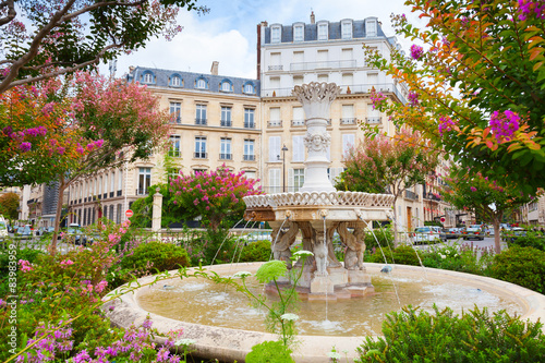 Old fountain and colorful flowers in Paris
