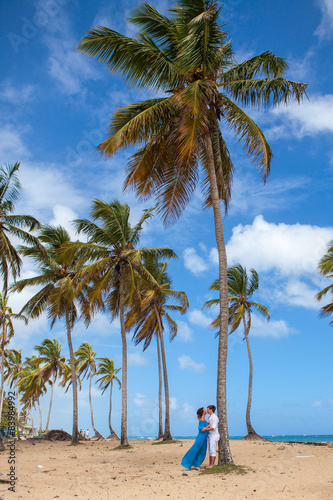 Beach couple walking on romantic travel near high palms.