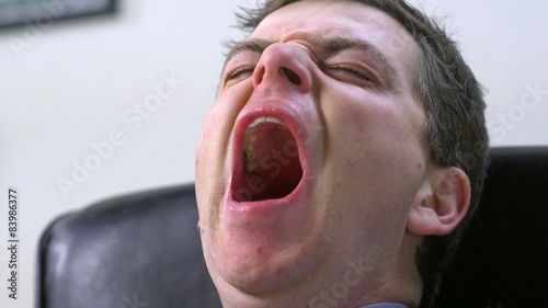 Young Business Executive Man sitting at desk, Yawning at Office