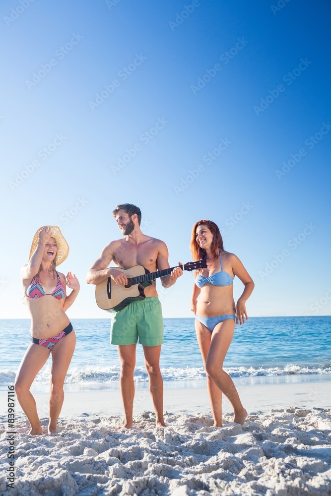 Handsome man playing guitar and his friends dancing Handsome man playing guitar and his friends dancing