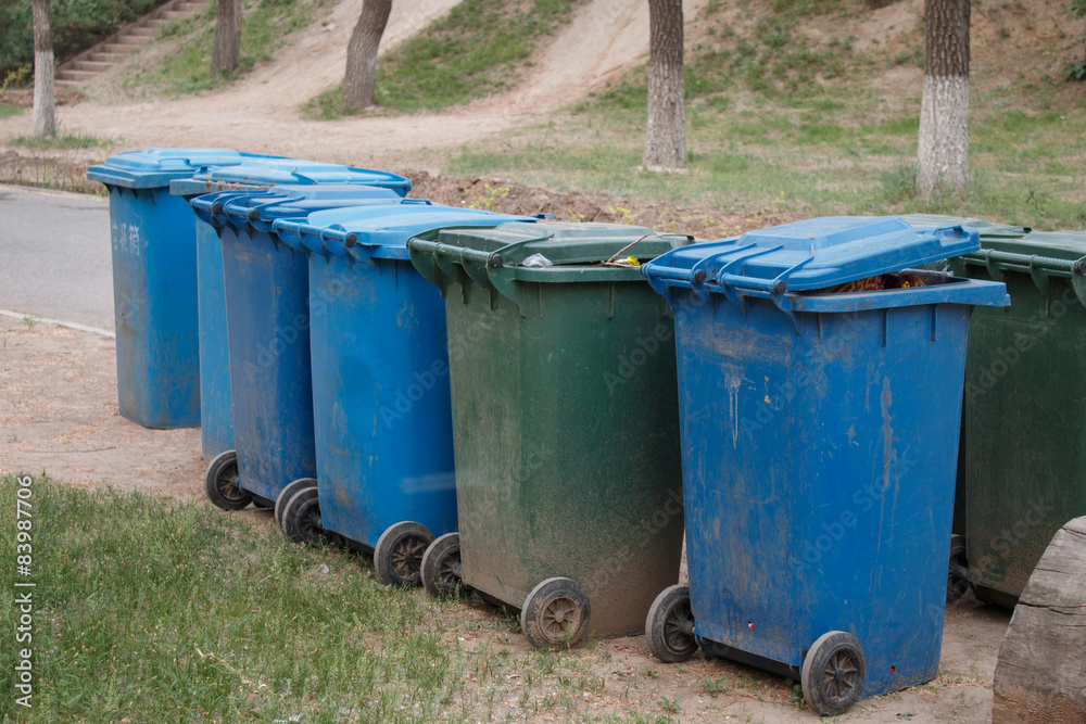 green and blue garbage bin in the park green and blue garbage bin in the park