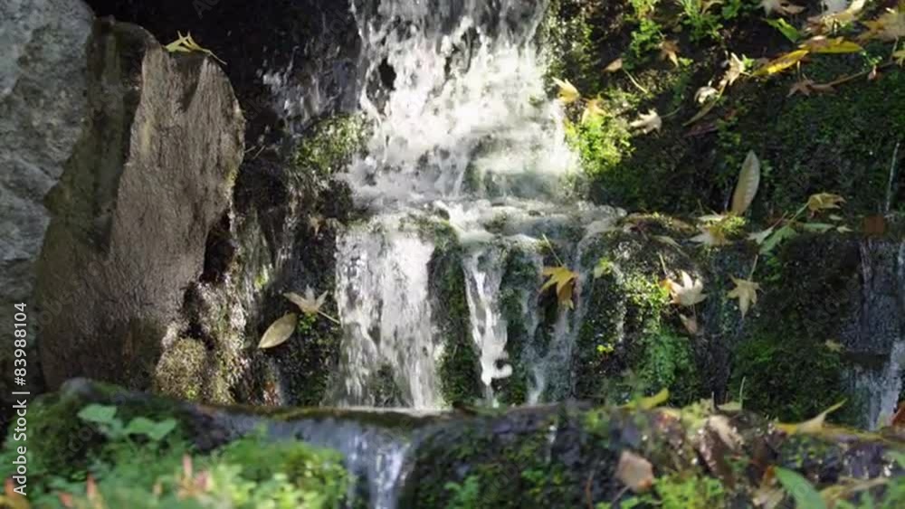 Slow motion shot of a small waterfall in a park Slow motion shot of a small waterfall in a park