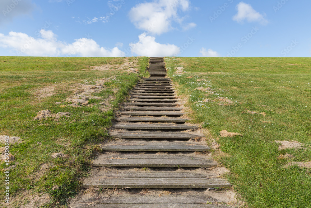 Wooden stairs upon green hill with blue sky