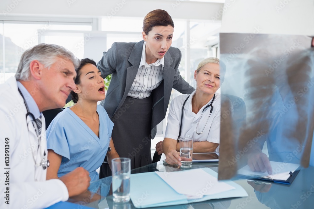 © WavebreakMediaMicro - Team of doctors and businesswoman examining xray