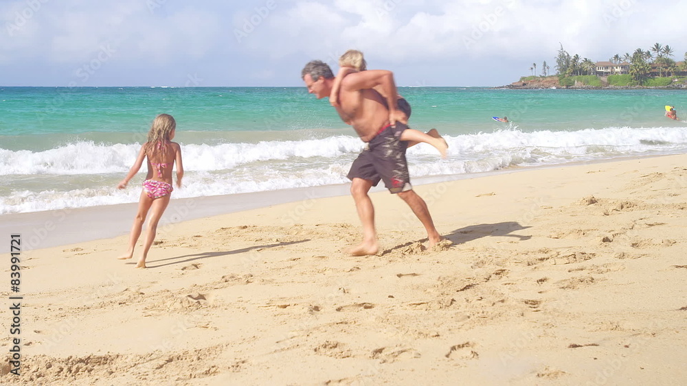 A man runs around the beach with a boy and girl A man runs around the beach with a boy and girl