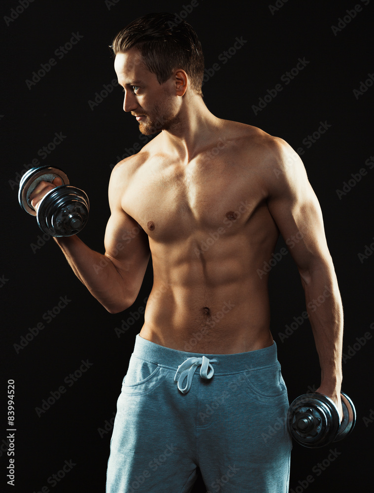 Athletic attractive man with dumbbells on the black Athletic attractive man with dumbbells on the black