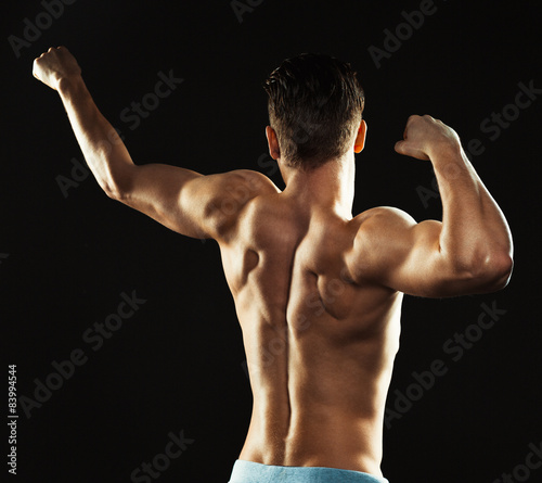 Athletic man showing his back on the black background