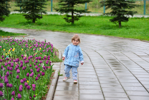 Little girl near the flower beds with tulips © olgavolodina