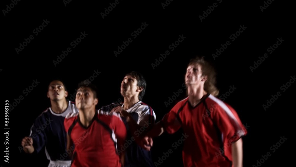 Four soccer players jump at the same time in an attempt to head the ball Four soccer players jump at the same time in an attempt to head the ball