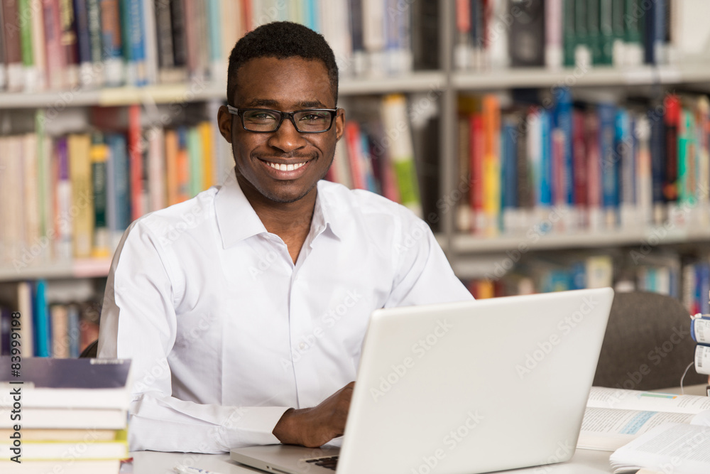 Young Student Using His Laptop In A Library Young Student Using His Laptop In A Library