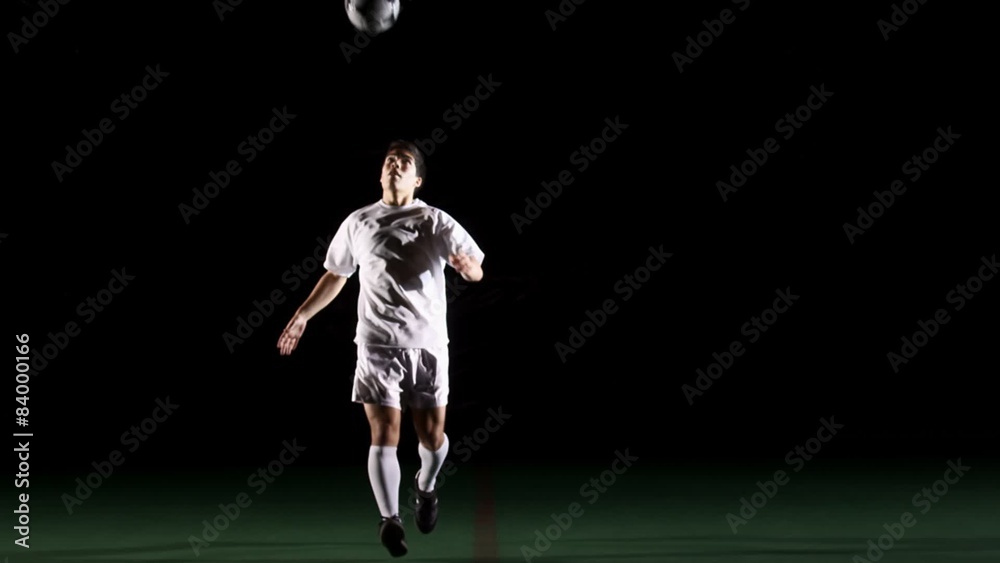 Isolated soccer player on black does tricks with the ball Isolated soccer player on black does tricks with the ball