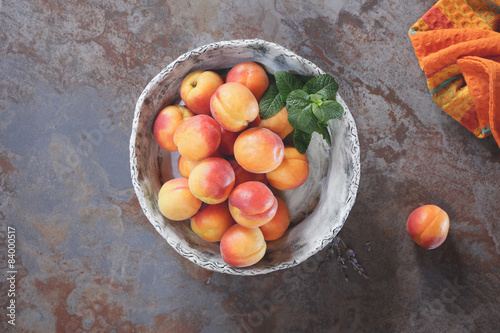 Apricots in ceramics bowl on a rustic stone surface