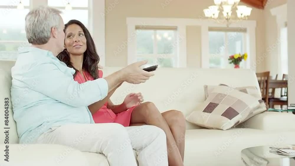 A man turns off the TV with his remote while sitting on the couch with a woman, then they hug A man turns off the TV with his remote while sitting on the couch with a woman, then they hug