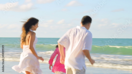 A family runs towards the water at the beach
