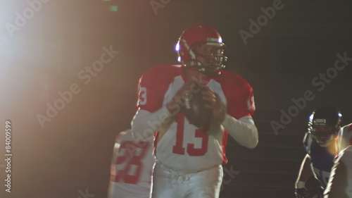 A quarterback receiving a snap from the center and dropping back to throw a pass