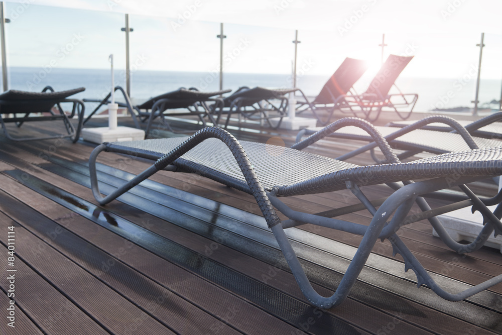Lounge sunbeds near swimming pool with the sunlight in the background Lounge sunbeds near swimming pool with the sunlight in the background