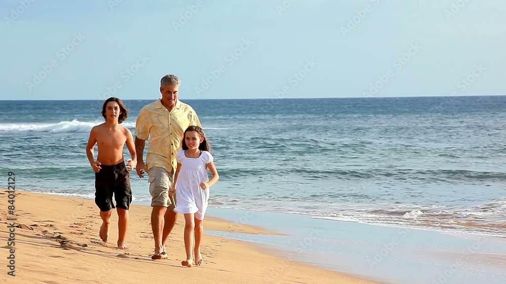 A family running through the waves on a beach in Hawaii A family running through the waves on a beach in Hawaii
