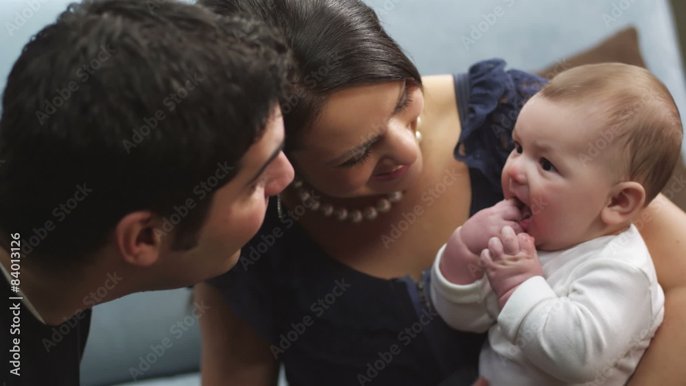 A young man and woman sit on the couch and plays with their baby A young man and woman sit on the couch and plays with their baby