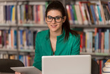 Happy Female Student Working With Laptop In Library