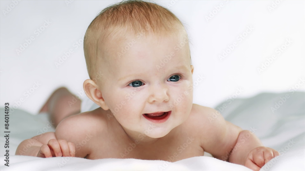 Cute baby on its belly smiles for camera. Medium shot Cute baby on its belly smiles for camera. Medium shot