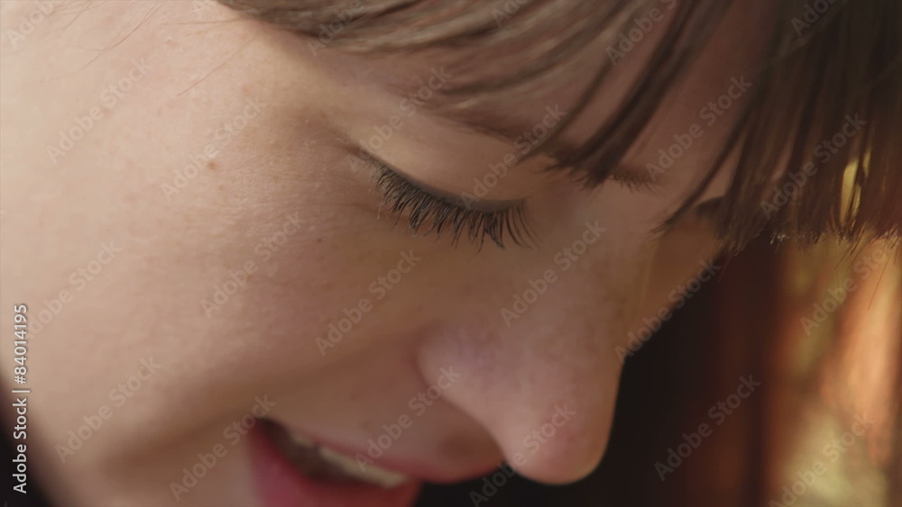 Close up of a smiling young woman who then looks up and smiles at the camera Close up of a smiling young woman who then looks up and smiles at the camera