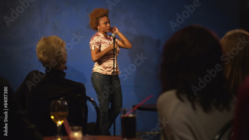 A young woman is up on stage giving a comedy performance