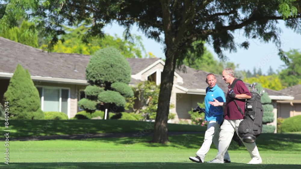 Two older gentlemen walk down a golf course together and talk Two older gentlemen walk down a golf course together and talk