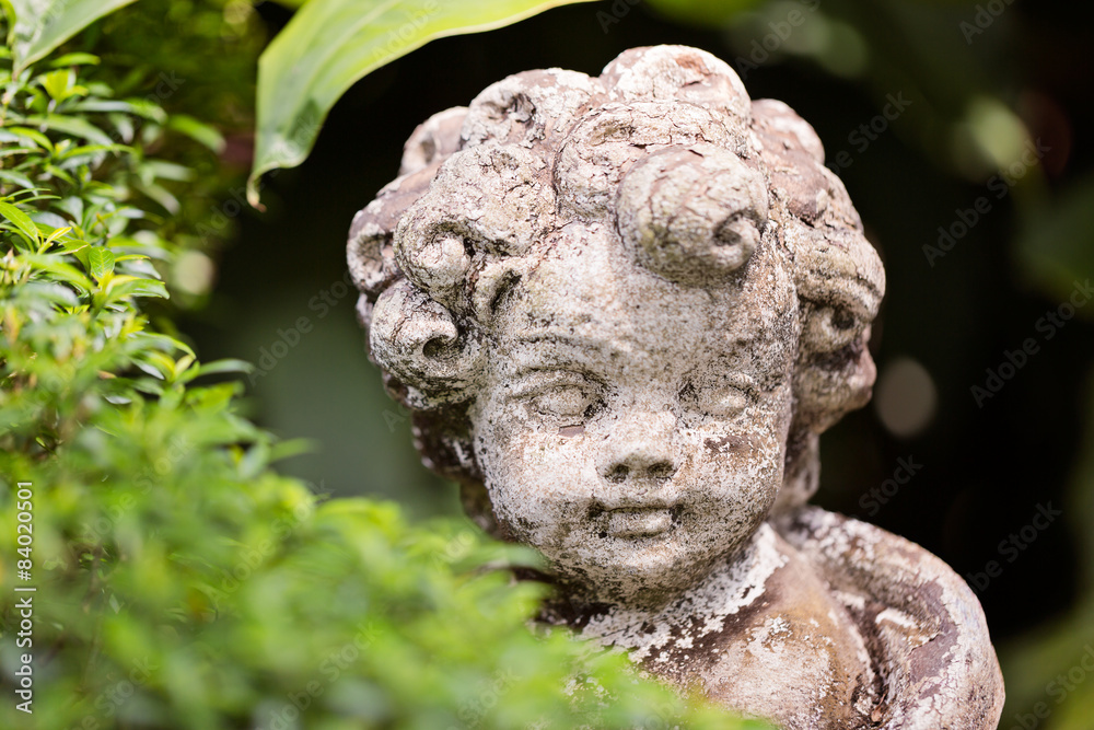 Old statue of an infant angel or cupid in the garden