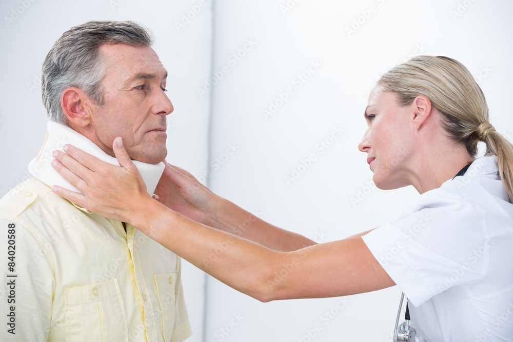 Doctor examining patient wearing neck brace Doctor examining patient wearing neck brace