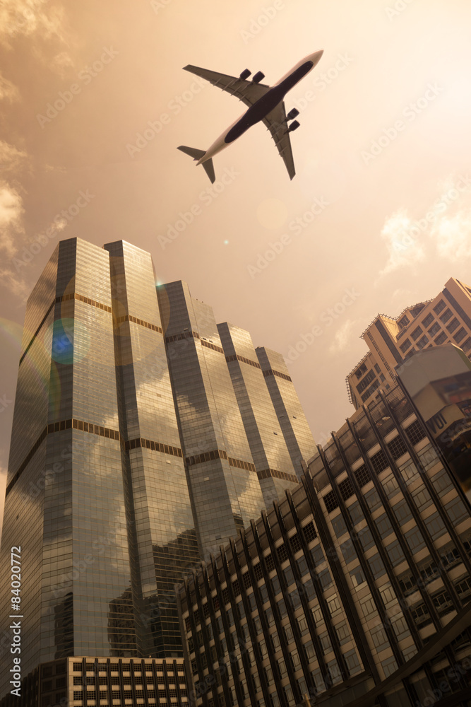 Airplane in golden sky with modern buildings