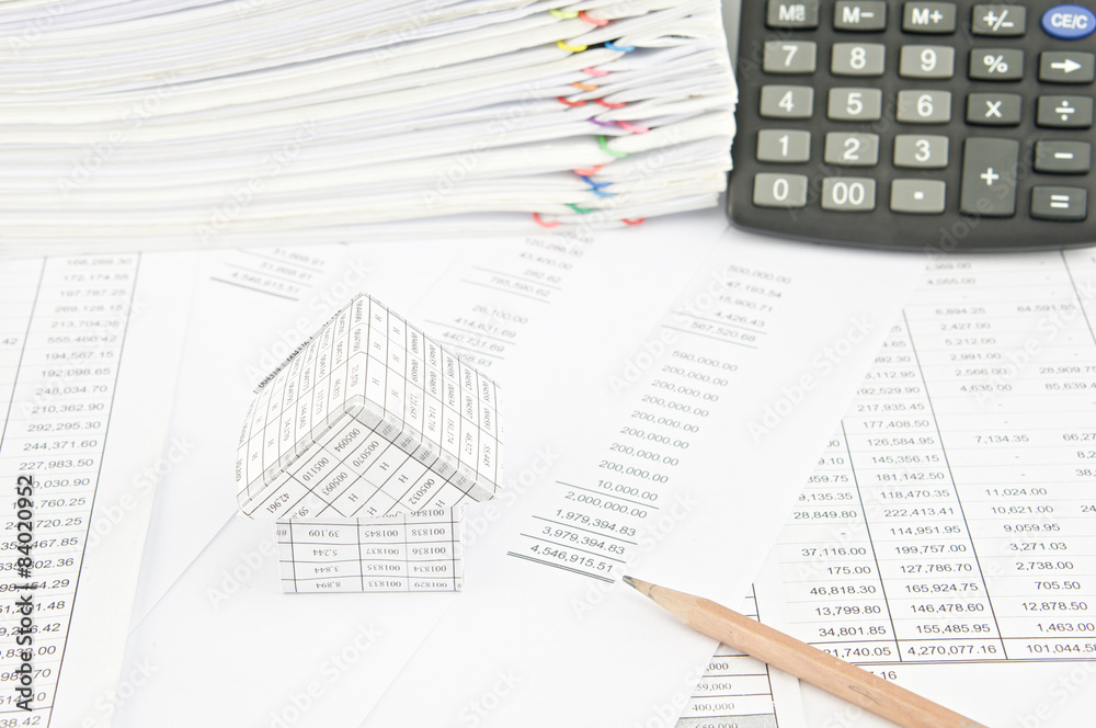 Brown pencil and house on balance sheet Brown pencil and house on balance sheet
