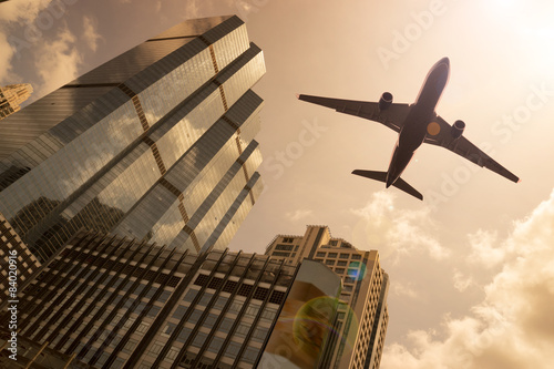 Airplane in golden sky with modern buildings