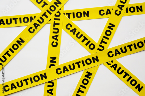 Yellow Caution tapes crossing on white background photo