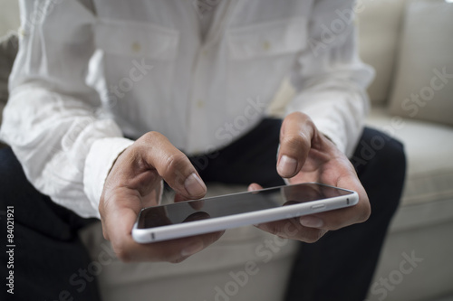 Men are using a mobile phone on the sofa