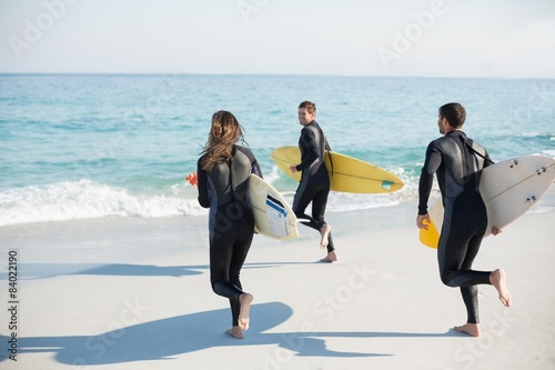 Group of friends on wetsuits with a surfboard on a sunny day