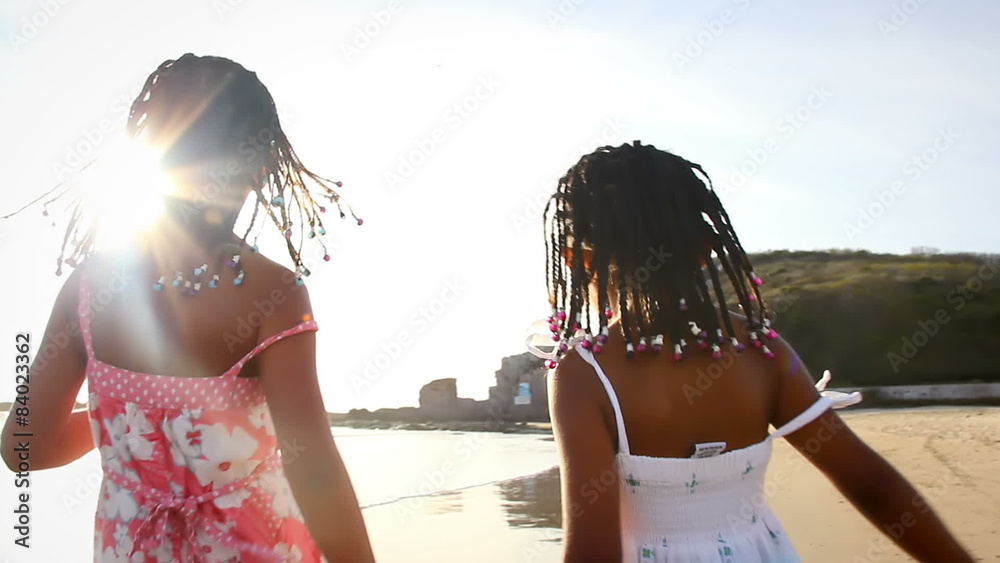 Young girls running and holding hands in the surf on a beach in Mexico