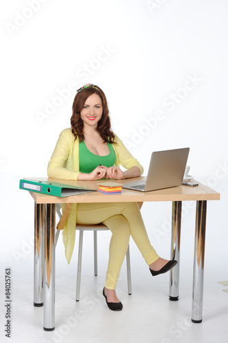 Happy young successful woman working at desk with laptop