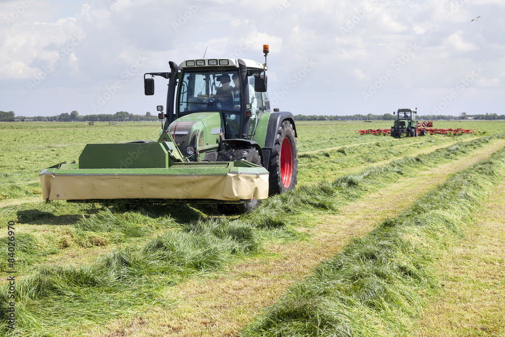 Fototapeta premium tractor and mower in green meadow in the netherlands