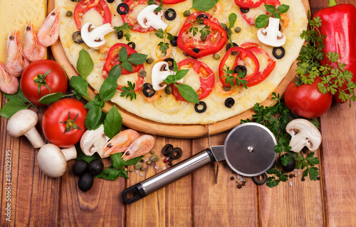 Pizza with ingridients and round knife