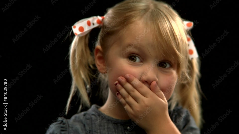 A young blonde girl with pigtails shushes with her finger A young blonde girl with pigtails shushes with her finger