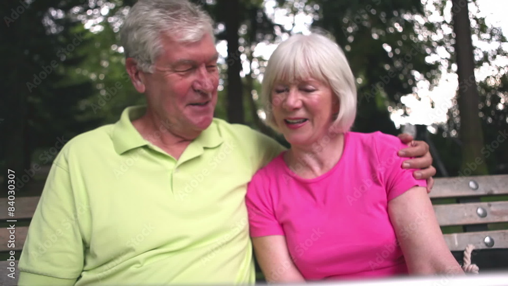 Baby boomer portrait of smiling couple sitting on a park bench. Medium shot. Baby boomer portrait of smiling couple sitting on a park bench. Medium shot.